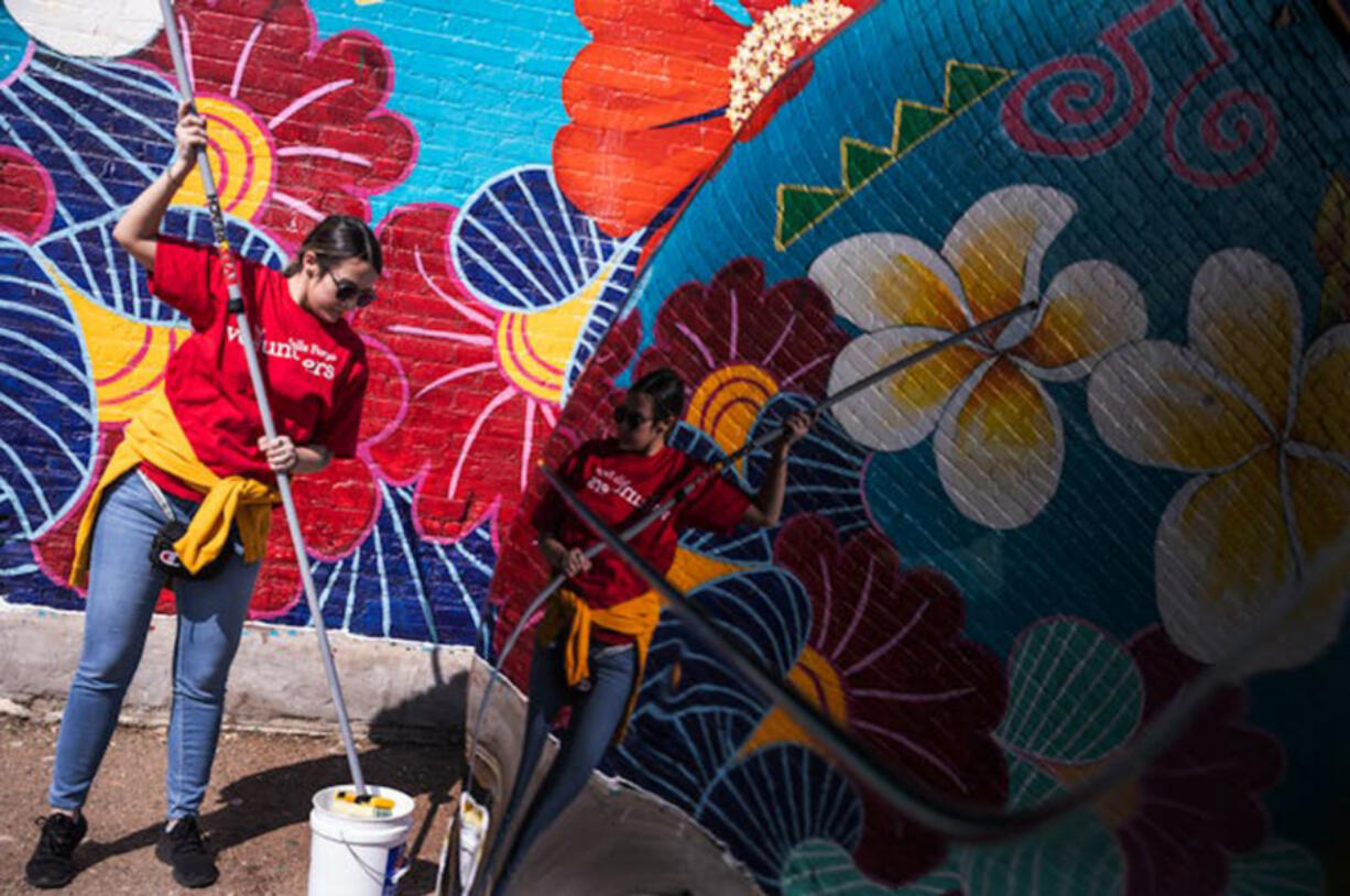 Anna Colakovic, a volunteer with Wells Fargo, rolls an anti-graffiti coating over a mural on Lake Street last month.