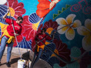 Anna Colakovic, a volunteer with Wells Fargo, rolls an anti-graffiti coating over a mural on Lake Street last month.