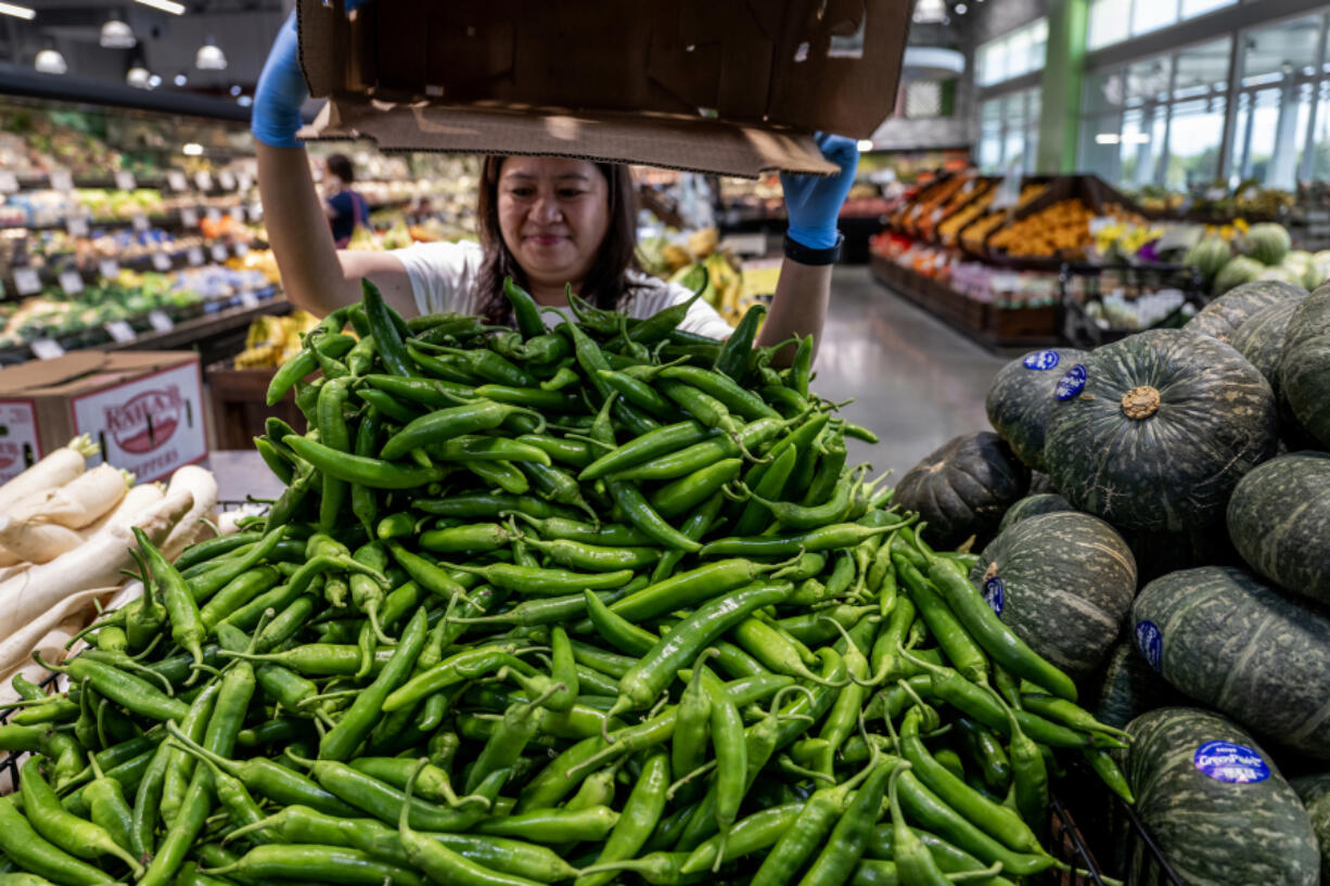 A store clerk adds more fresh sweet chilis to a display pile in the produce area at a Ranch 99 market on June 28, 2023, in Eastvale, California. A study by researchers at Harvard and UC San Francisco found that 91 percent of California service sector workers surveyed experienced at least one labor violation in the last year at work.
