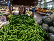 A store clerk adds more fresh sweet chilis to a display pile in the produce area at a Ranch 99 market on June 28, 2023, in Eastvale, California. A study by researchers at Harvard and UC San Francisco found that 91 percent of California service sector workers surveyed experienced at least one labor violation in the last year at work.