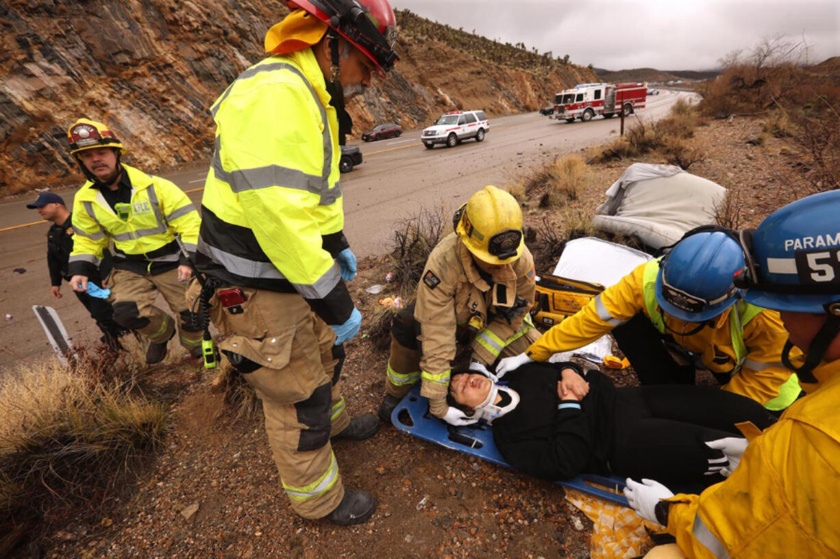 From left: San Bernardino County Fire Engineer Jeff Garcia, Capt. Dan Tellez, standing, paramedic Brian Bement, EMT Ray Barron and paramedic Eric Butikofer, right, with San Bernardino County Fire Protection District Station 53 in Baker, stabilize a car accident victim who was thrown from her vehicle along I-15 at Mountain Pass in Nipton.