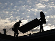 Jared Salvatore, left, and Garrison Riegel, of Celestar Solar, carry a solar panel onto a roof Nov. 30 in Schaumburg, Ill.