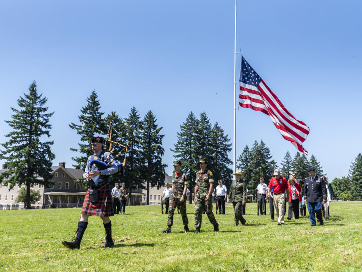 A parade of dignitaries follows Gustav Baur, left, as he plays the bagpipe during the 2023 Memorial Day Ceremony at Fort Vancouver National Historic Site.