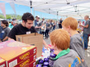 An IMPACT Camas-Washougal volunteer, left, verifies the contents of a food box in the spring of 2023.