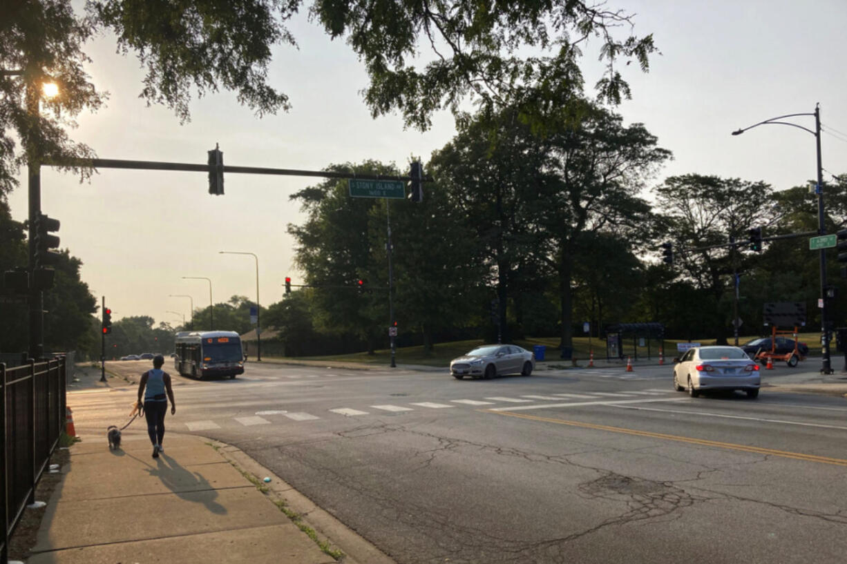 A pedestrian walks with a dog at the intersection of South Stony Island Avenue and East 63rd Street where the ShotSpotter technology is in use above the crossroads on Tuesday, Aug. 10, 2021, in Chicago.