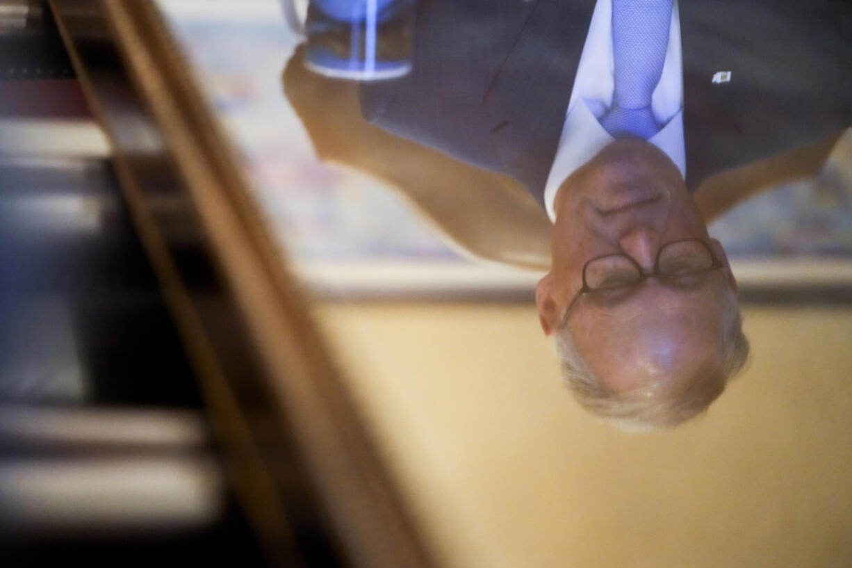 Washington Gov. Jay Inslee is reflected in a table as he prepares in his office before his State of the State address on the second day of the legislative session at the Washington state Capitol, Tuesday, Jan. 9, 2024, in Olympia, Wash.