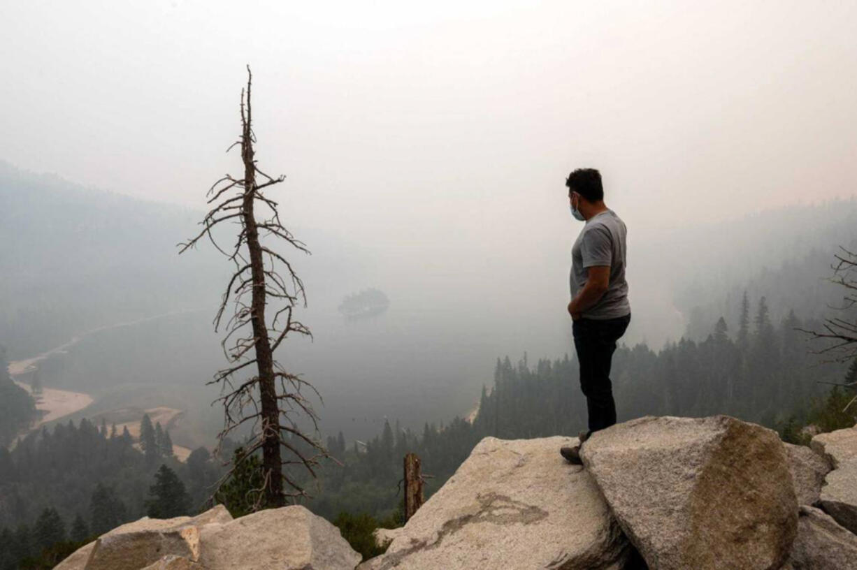 A man vacationing in the Lake Tahoe area stands above Emerald Bay as wildfire smoke from the Caldor Fire obscures Fannette Island in 2021. Researchers at UC Davis say as wildfire activity has grown, the state&rsquo;s pristine bodies of water have been affected by smoke.