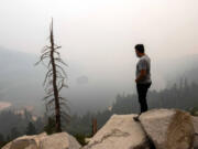 A man vacationing in the Lake Tahoe area stands above Emerald Bay as wildfire smoke from the Caldor Fire obscures Fannette Island in 2021. Researchers at UC Davis say as wildfire activity has grown, the state&rsquo;s pristine bodies of water have been affected by smoke.