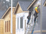 Construction workers hold a piece of siding in place at a development in east Vancouver. The city has awarded millions of local and federal dollars to housing and homelessness services that will produce hundreds of affordable housing units.