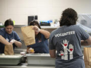 A crew of volunteers at local nonprofit Share Vancouver assemble sack lunches in the kitchen at Fort Vancouver High School in July. State schools superintendent Chris Reykdal announced a new program last week that will provide children across Washington with $120 meal cards to buy groceries throughout the summer.