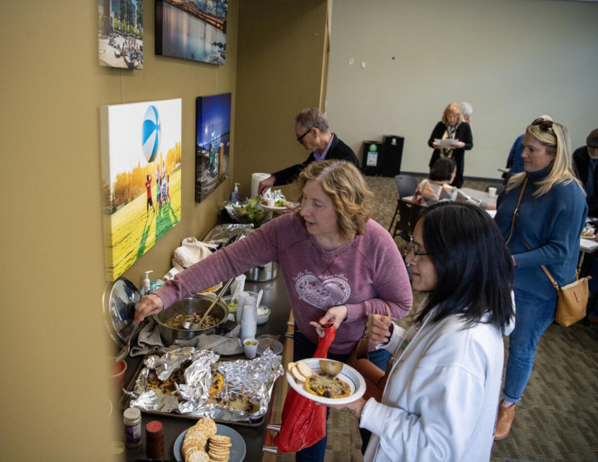 Leah Perkel, from left, puts a serving spoon into a dish while Monica Zazueta prepares a plate. They attended Mayor Anne McEnerny-Ogle&rsquo;s Wednesday workshop that taught people how to safely serve food to homeless people. Participants brought recipes that work for large groups.