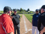 Umpire John Telyea, second from left, talks with Camas JV coach Liam Fitzpatrick, left, Skyview JV coach Trevor Mueller, second from right, and umpire Fritz Porter on April 23 at Camas High School. Telyea is one of a handful of baseball and softball high school umpires in Clark County wearing body cameras as part of a Washington Interscholastic Activities Association pilot program.