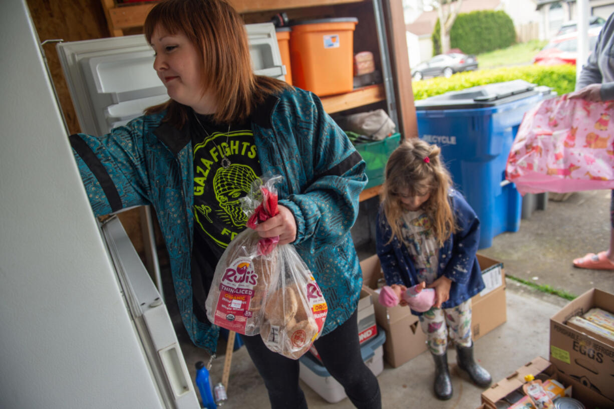 Karissa Halstrom and her daughter Frankie, 6, fill one of the Free Fridge. Halstrom is fighting for a more environmentally secure future for Frankie.