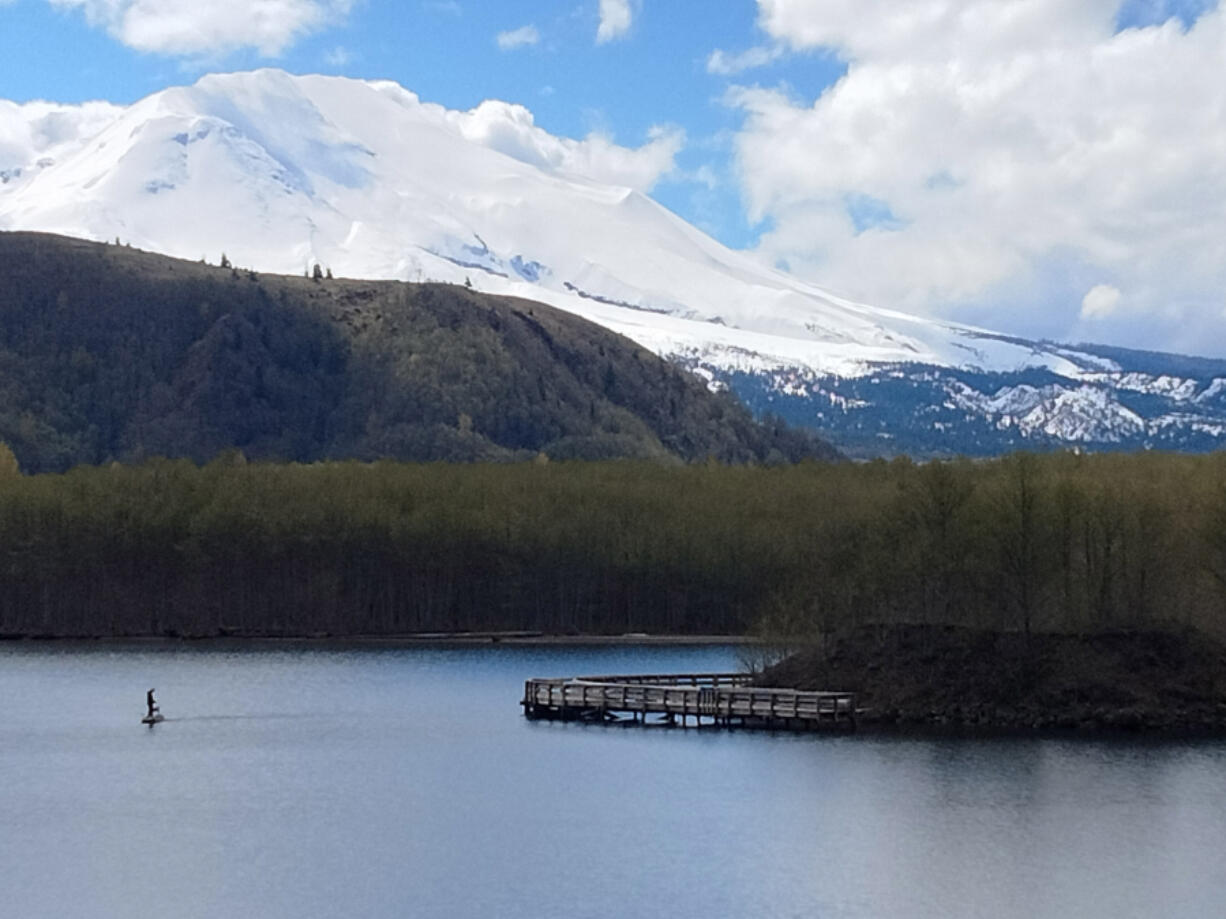 The broken peak of Mount St. Helens looms over a lone fisherman at Coldwater Lake.