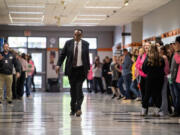 Battle Ground music director Greg McKelvey walks down the main hallway of Battle Ground High School to applause Wednesday during a ceremony at Battle Ground High School. McKelvey, who is retiring at the end of this school year, has been named grand marshal of the 2024 Portland Rose Festival Grand Floral Parade.