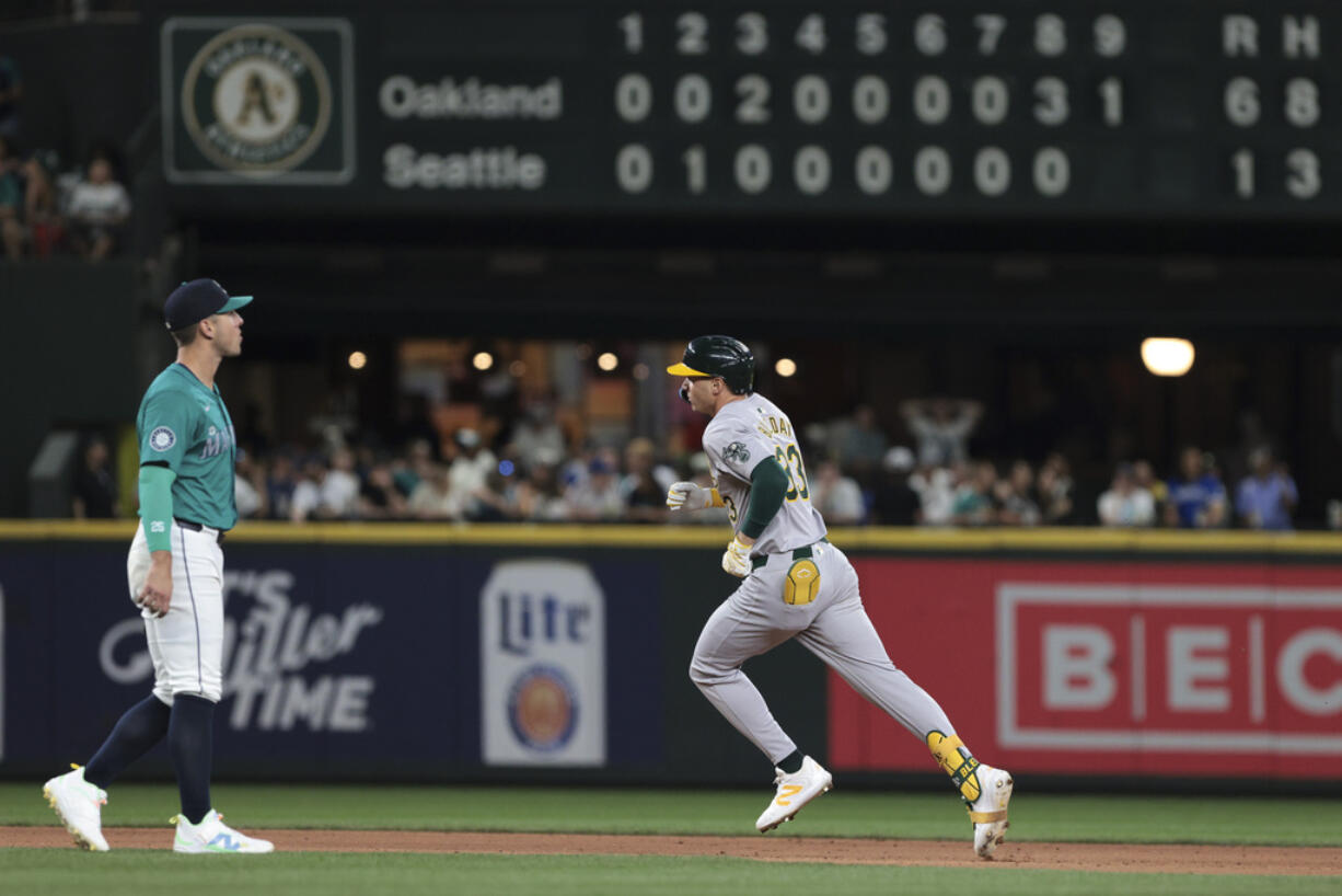 Oakland Athletics' JJ Bleday rounds second on a two-run home run, next to Seattle Mariners shortstop Dylan Moore during the ninth inning of a baseball game Saturday, May 11, 2024, in Seattle.