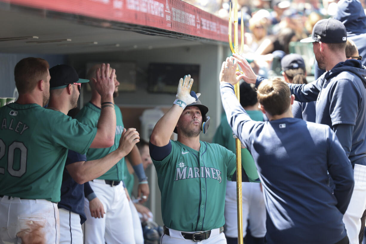 Seattle Mariners' Ty France, center, holds a trident in the dugout after his solo home run during against the Kansas City Royals during the fourth inning of a baseball game Wednesday, May 15, 2024, in Seattle.