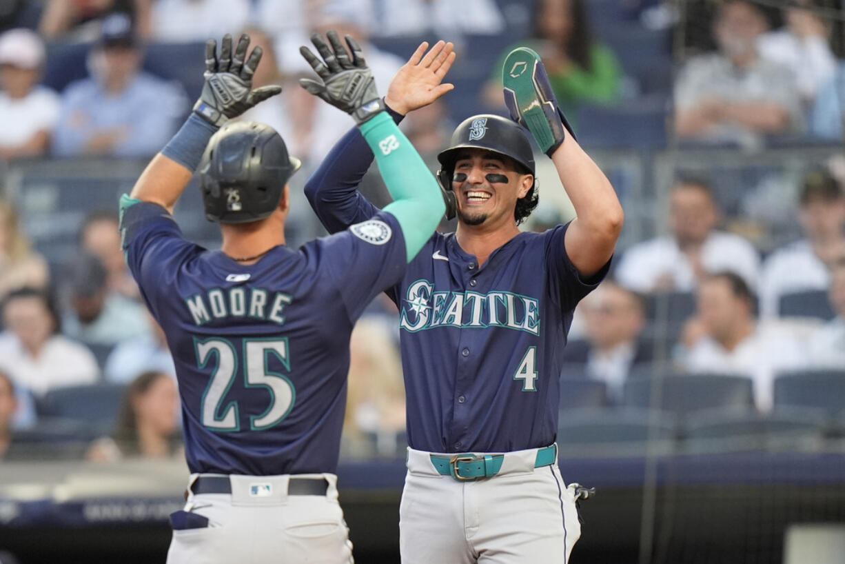 Seattle Mariners' Josh Rojas (4) celebrates with Dylan Moore (25) after Moore hit a two-run home run during the third inning of a baseball game against the New York Yankees, Tuesday, May 21, 2024, in New York.