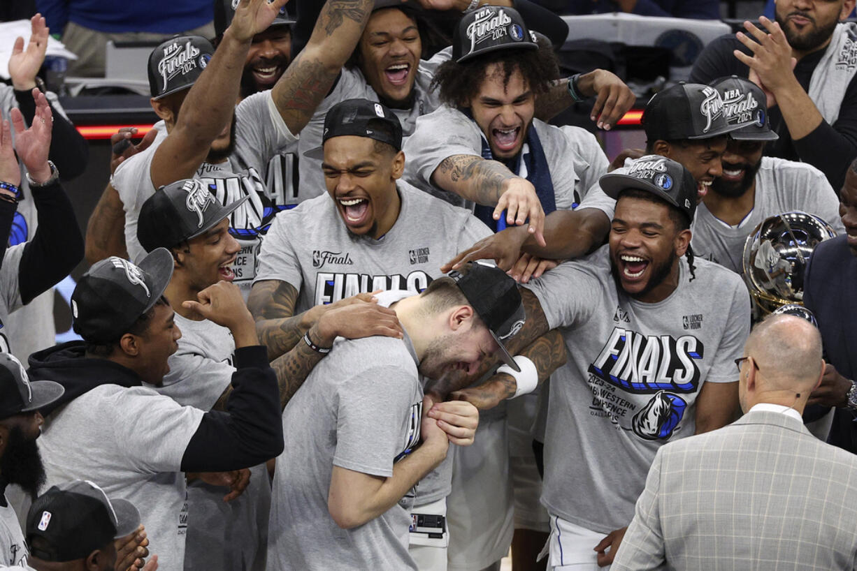 Dallas Mavericks guard Luka Doncic, center, celebrates with teammates after Game 5 of the Western Conference finals in the NBA basketball playoffs against the Minnesota Timberwolves, Thursday, May 30, 2024, in Minneapolis. The Mavericks won 124-103, taking the series 4-1 and moving on to the NBA Finals.