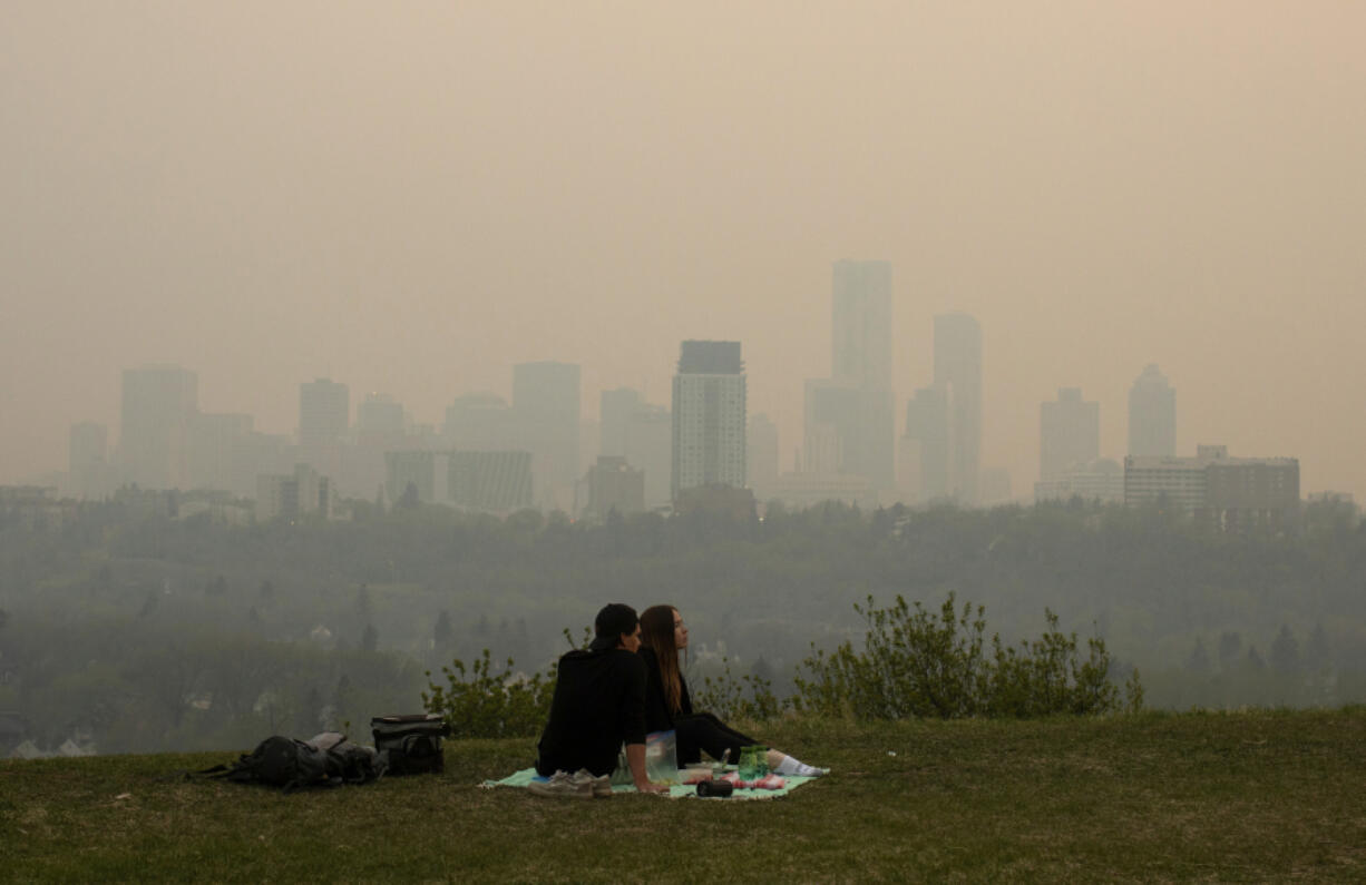 Smoke from wildfires blankets the city as a couple has a picnic in Edmonton, Alberta, Saturday, May 11, 2024.