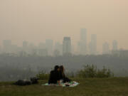 Smoke from wildfires blankets the city as a couple has a picnic in Edmonton, Alberta, Saturday, May 11, 2024.