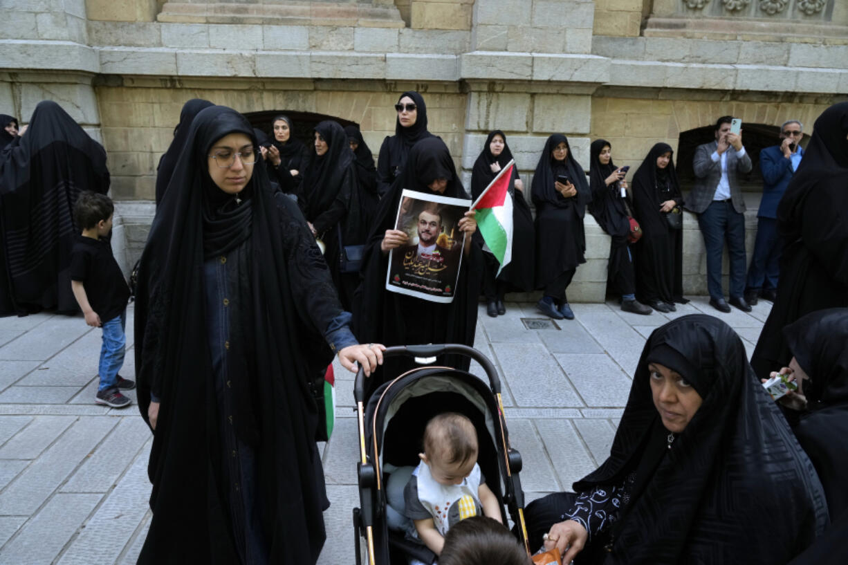 A woman holds a poster of the late Iranian Foreign Minister Hossein Amirabdollahian, who was killed in a helicopter crash along with President Ebrahim Raisi, and a Palestinian flag during his funeral ceremony at the foreign ministry in Tehran, Iran, Thursday, May 23, 2024. The death of Raisi, Amirabdollahian and six others in the crash on Sunday comes at a politically sensitive moment for Iran, both at home and abroad.