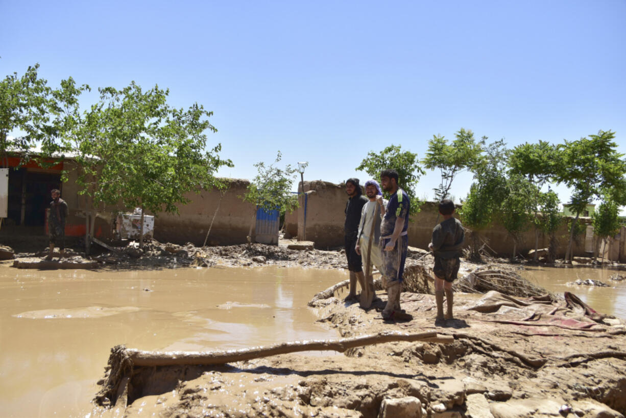 People stand near damaged homes after heavy flooding in Baghlan province, in northern Afghanistan, Sunday, May 12, 2024. Victims of the devastating floods in northern Afghanistan are burying the dead and looking for the loved ones still missing.