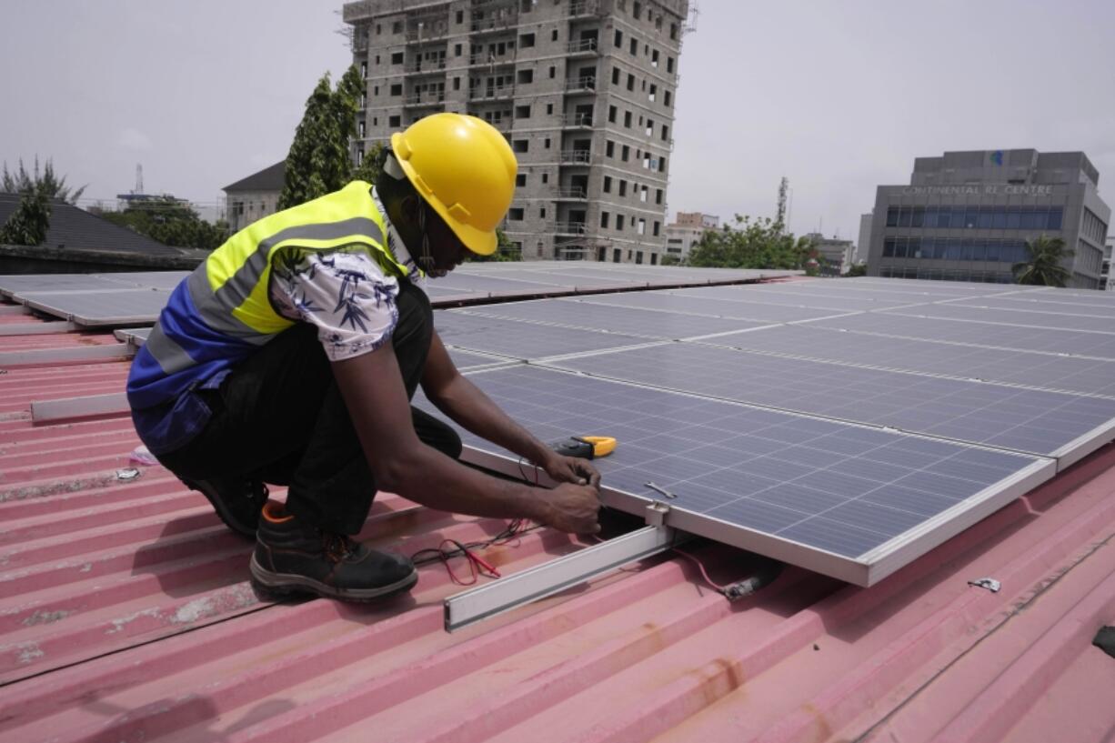 Oladapo Adekunle, an engineer with Rensource Energy, installs solar panels on a roof of a house in Lagos, Nigeria, Thursday, March 21, 2024. Funding for climate tech startups in Africa from the private sector is growing, but there&rsquo;s still a long way to go.