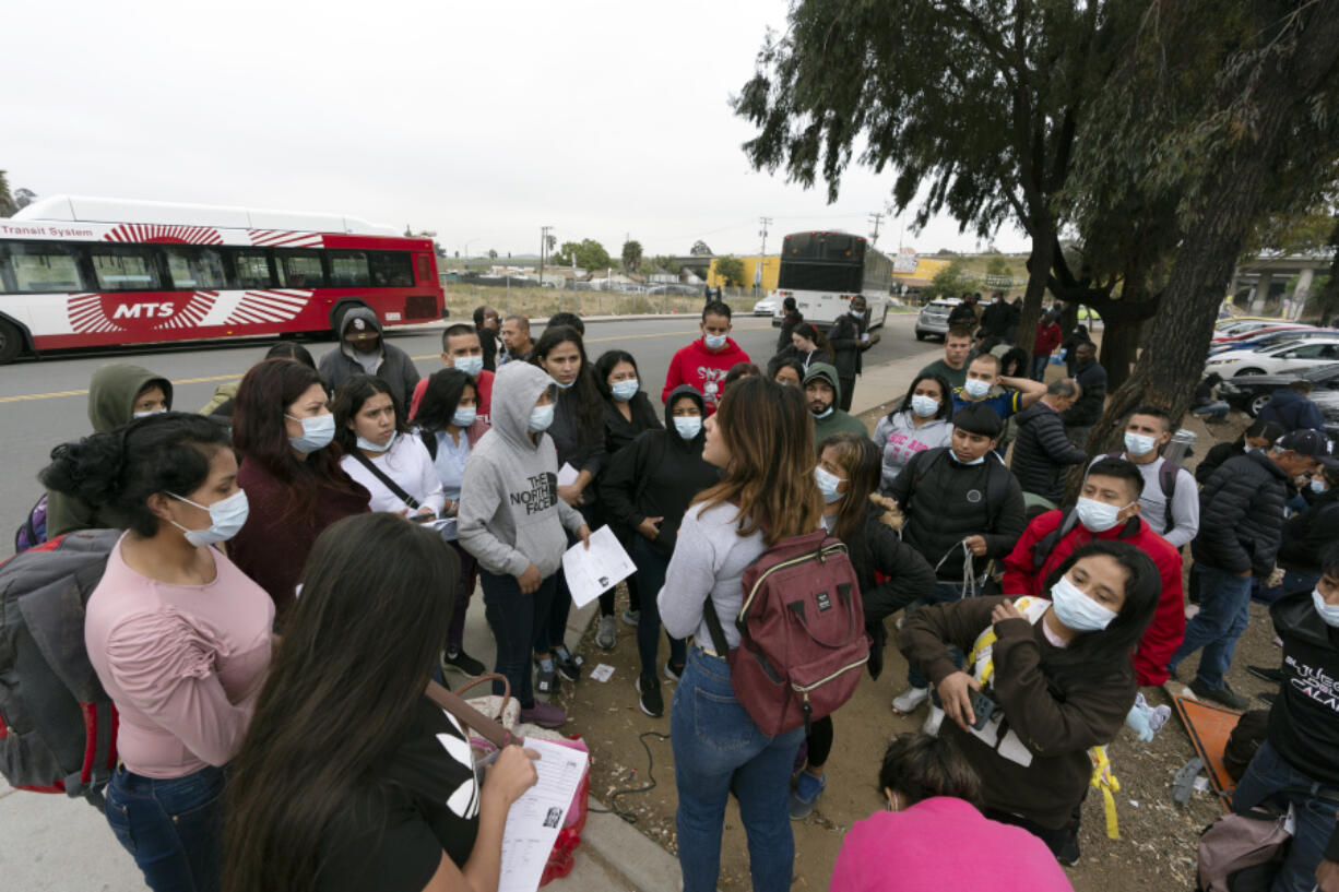 FILE - Migrants listen to a volunteer in a parking lot after being detained and processed for asylum by U.S. authorities, April 12, 2024, in San Diego. A new Biden administration rule aims to speed up asylum processing at the southern border, enabling it to quickly reject a limited group of people believed to have committed serious crimes or who have terrorist links. The change announced May 9 comes during an election year when immigration is a key issue.