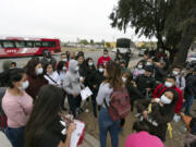 FILE - Migrants listen to a volunteer in a parking lot after being detained and processed for asylum by U.S. authorities, April 12, 2024, in San Diego. A new Biden administration rule aims to speed up asylum processing at the southern border, enabling it to quickly reject a limited group of people believed to have committed serious crimes or who have terrorist links. The change announced May 9 comes during an election year when immigration is a key issue.