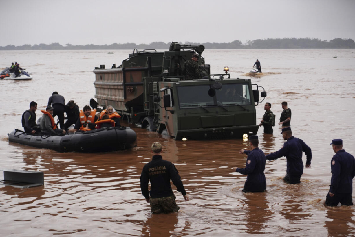 Brazilian soldiers and federal police evacuate residents from an area flooded by heavy rains in Porto Alegre, Rio Grande do Sul state, Brazil, Saturday, May 4, 2024.