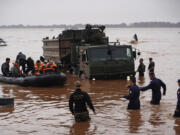 Brazilian soldiers and federal police evacuate residents from an area flooded by heavy rains in Porto Alegre, Rio Grande do Sul state, Brazil, Saturday, May 4, 2024.