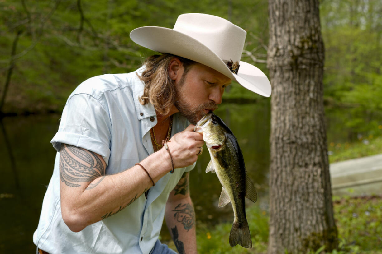 Brian Kelley kisses a fish he caught from a pond outside his cabin April 17 in Nashville, Tenn.