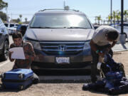 Migrants check their baggage at a parking lot after being detained and processed for asylum by U.S authorities Tuesday, May 7, 2024, in San Diego.