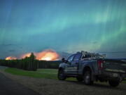 This photo provided by the Ministry of Water, Land and Resource Stewardship shows a wildfire,  Aurora Borealis  overhead, near Fort Nelson, British Columbia Saturday, May 11, 2024. An intense wildfire could hit a town in western Canada on Monday, based on forecasts of strong winds that have been fueling the out-of-control blaze which has already forced the evacuation of thousands, fire experts and officials warned.