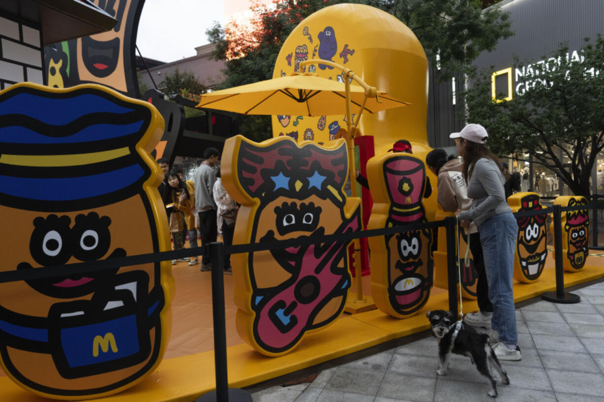 A woman with a dog looks into an attraction promoting the western fast food chain McDonald&rsquo;s in Beijing, Saturday, May 25, 2024.