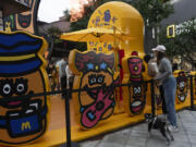 A woman with a dog looks into an attraction promoting the western fast food chain McDonald&rsquo;s in Beijing, Saturday, May 25, 2024.