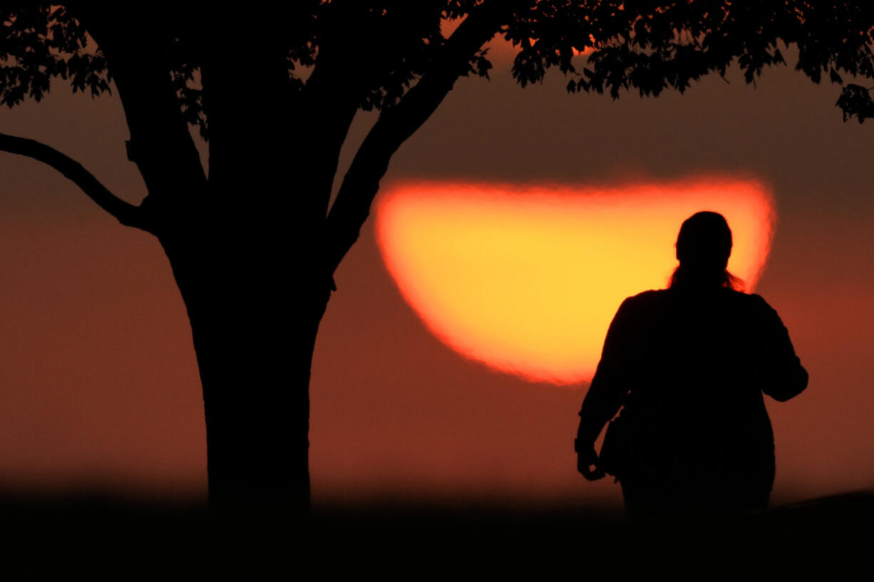 FILE - A woman watches the sun set on a hot day, Aug. 20, 2023, in Kansas City, Mo. A new study on Tuesday, May 14, 2024, finds that the broiling summer of 2023 was the hottest in the Northern Hemisphere in more than 2,000 years.