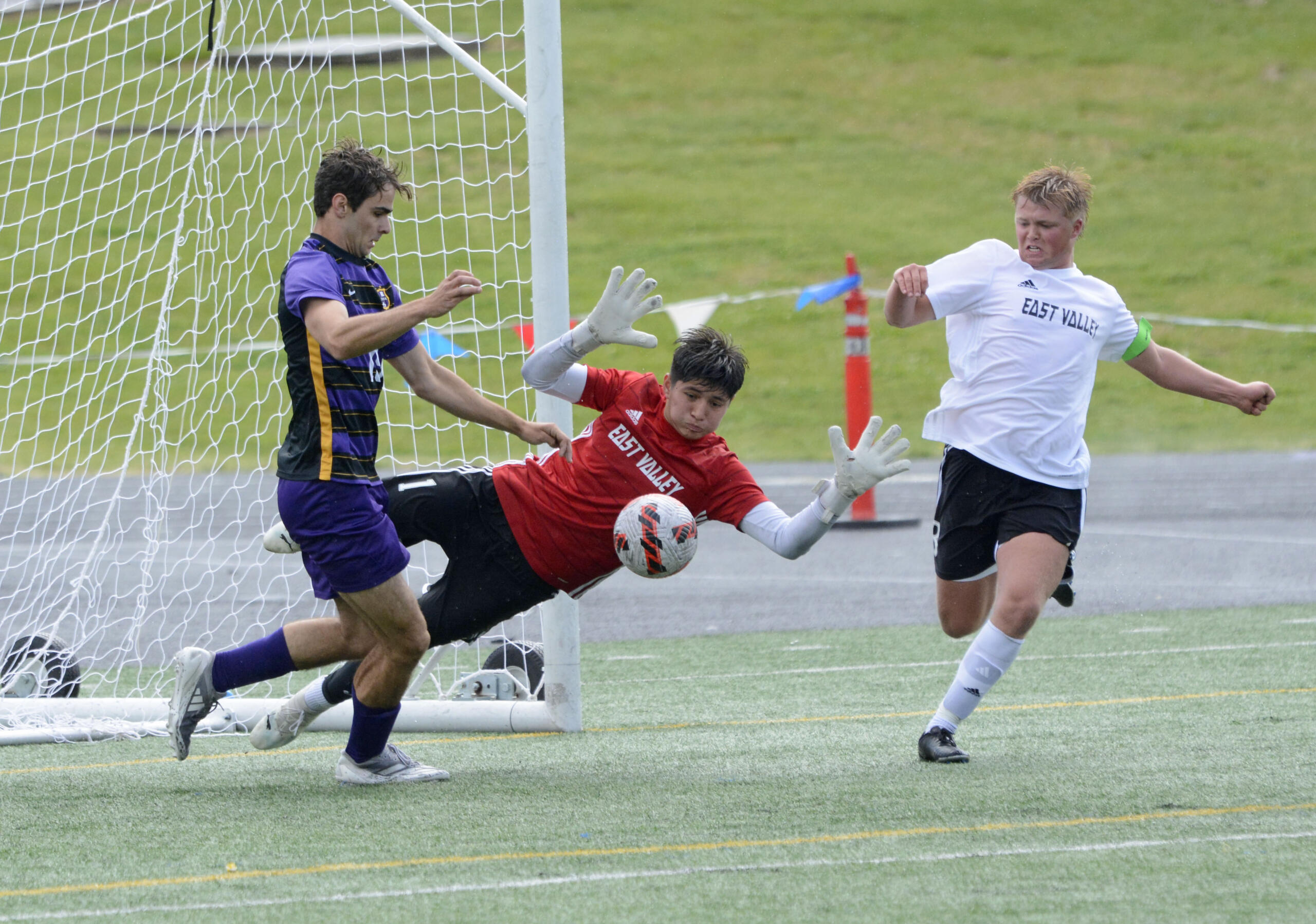 East Valley goalkeeper Samuel Gonzalez-Salas, center, and center back Jacob Russell, right, attempt to keep the ball away from Columbia River's Alex Snyder in front of goal during the Class 2A boys soccer state quarterfinals on Saturday, May 18, 2024, at Columbia River High School.