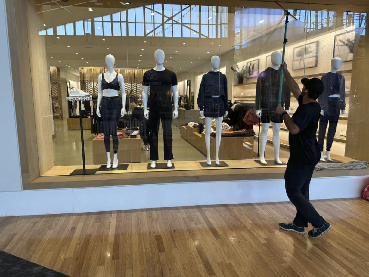 FILE - A cleaner works on the display window of a clothing store in a mall on April 29, 2024, in Lone Tree, Colo. On Friday, May 31, 2024, the Commerce Department issues its report on consumer spending for April.