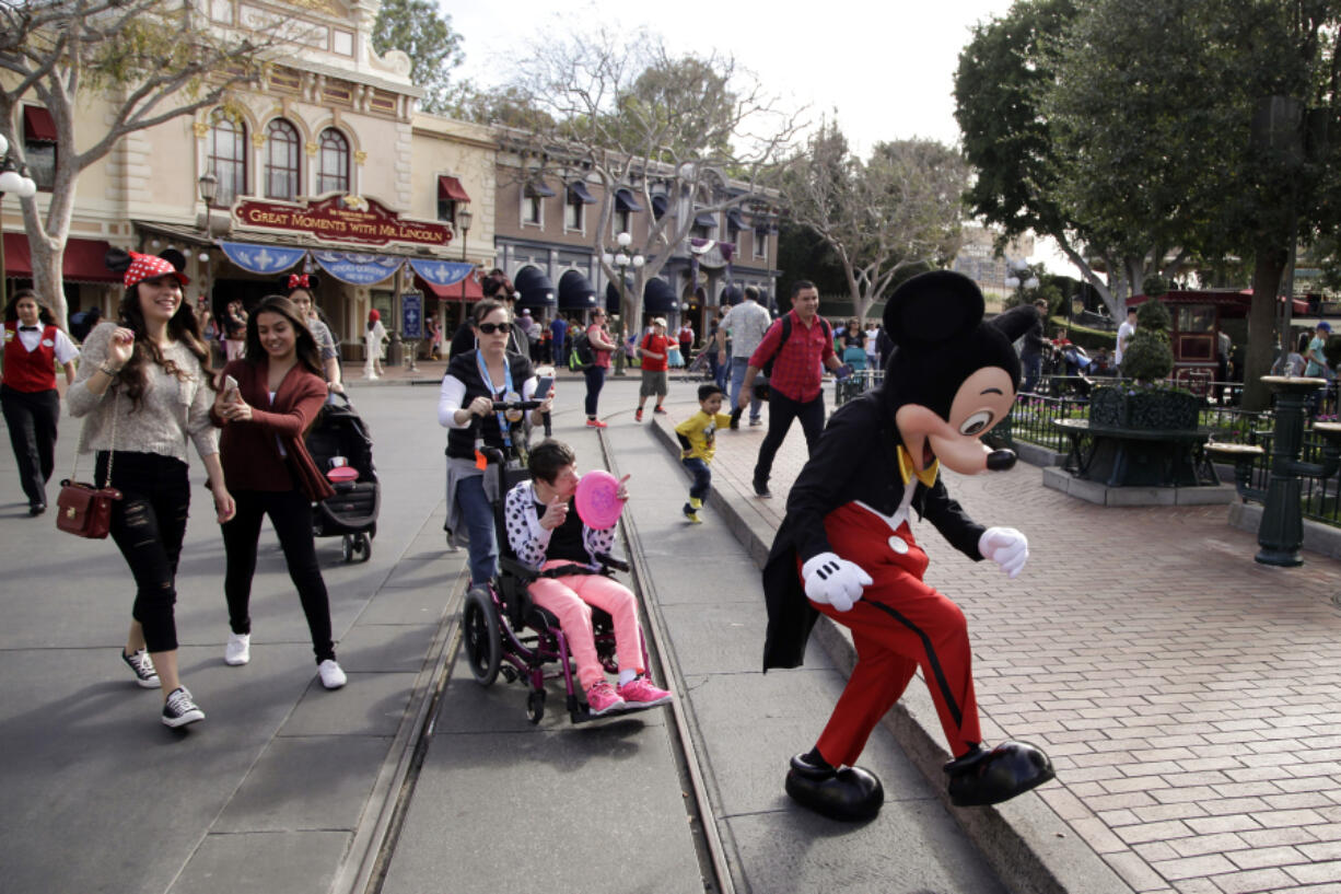 FILE - Visitors follow Mickey Mouse for photos at Disneyland, Jan. 22, 2015, in Anaheim, Calif. Disneyland performers who help bring Mickey Mouse, Cinderella and other beloved characters to life at the Southern California resort chose to unionize following a three-day vote culminating on Saturday, May 18, 2024. (AP Photo/Jae C.