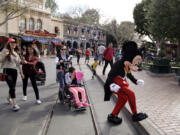 FILE - Visitors follow Mickey Mouse for photos at Disneyland, Jan. 22, 2015, in Anaheim, Calif. Disneyland performers who help bring Mickey Mouse, Cinderella and other beloved characters to life at the Southern California resort chose to unionize following a three-day vote culminating on Saturday, May 18, 2024. (AP Photo/Jae C.