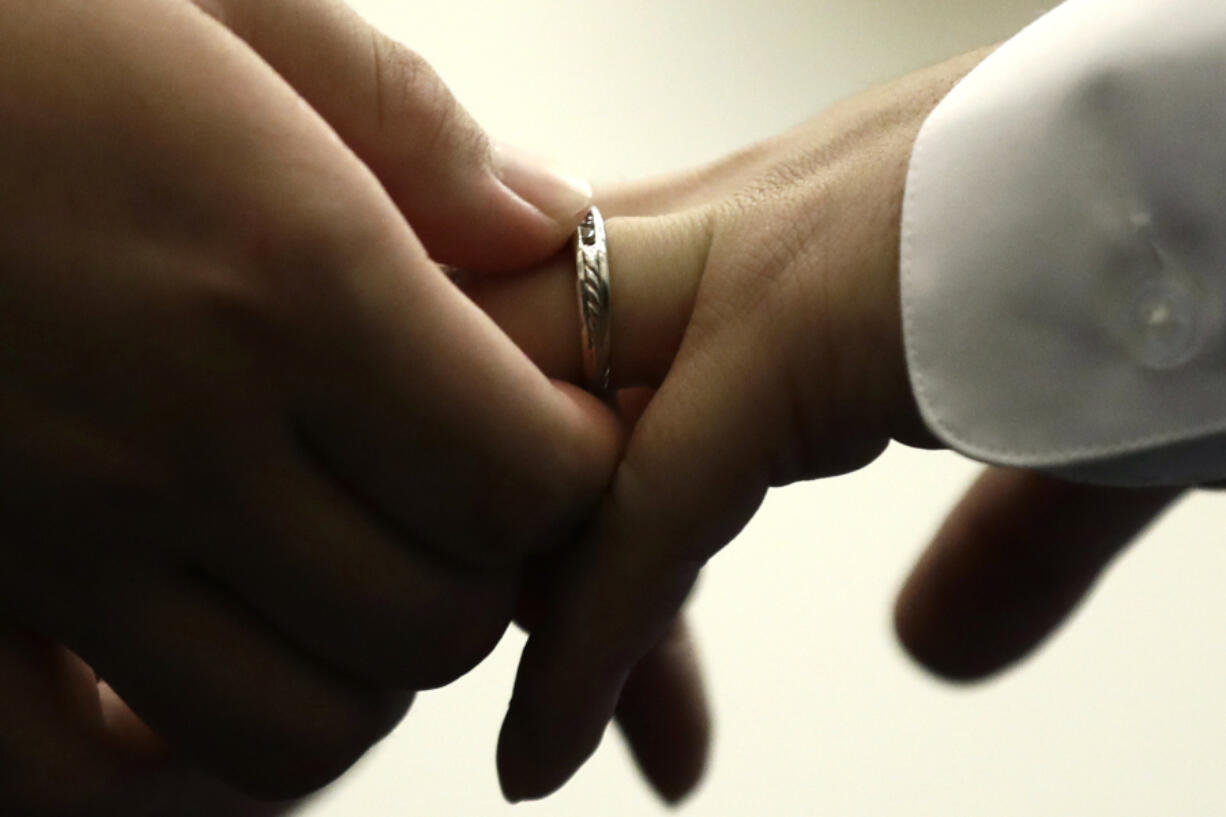 FILE - A couple exchanges wedding bands at City Hall in Philadelphia on Oct. 11, 2018. Divorce registries are part of a trend toward breaking the stigma of broken marriages, along with divorce parties and formal divorce announcements akin to wedding and marriage news.