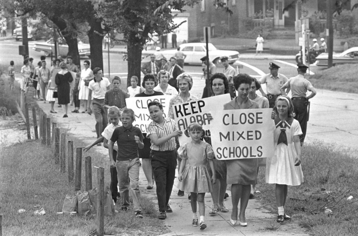 FILE - Mothers carrying protest signs accompany their children to Graymont Elementary School in Birmingham, Ala., which was opened on an integrated basis, Sept. 4, 1963. Friday, May 17, 2024, marks 70 years since the U.S. Supreme Court ruled that separating children in schools by race was unconstitutional. On paper, Brown v. Board of Education still stands. In reality, school integration is all but gone, the victim of a gradual series of court cases that slowly eroded it, leaving little behind.