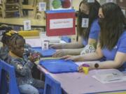 Jenna Carodiskey-Wiebe, assistant teacher with ECEAP, right, watches as two-year-old Zakiah Jatta plays with Play-Doh in her classroom  at Akin&rsquo;s Early Learning Center in Auburn, Wash., Tuesday, March 26, 2024. Washington is doing more to help families access and afford child care, but huge gaps remain. Early ECEAP provides free child care and family support services to infants and toddlers from low-income households. But there are only 178 spots funded in the entire state. Some of those spots are at Akin&rsquo;s early learning center in Auburn. (Ellen M.