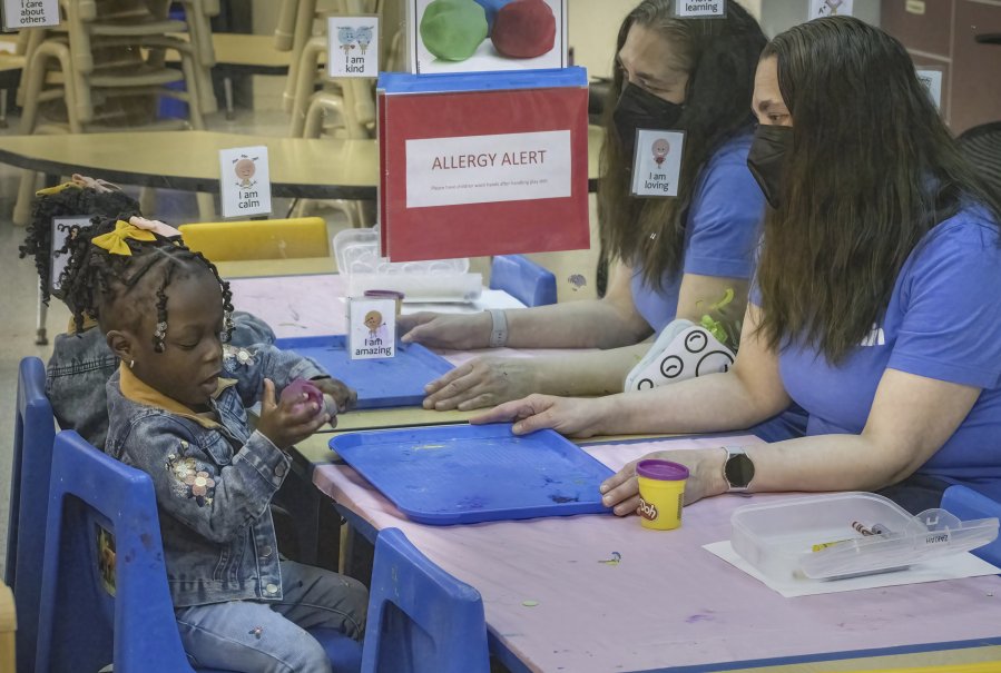 Jenna Carodiskey-Wiebe, assistant teacher with ECEAP, right, watches as two-year-old Zakiah Jatta plays with Play-Doh in her classroom  at Akin&rsquo;s Early Learning Center in Auburn, Wash., Tuesday, March 26, 2024. Washington is doing more to help families access and afford child care, but huge gaps remain. Early ECEAP provides free child care and family support services to infants and toddlers from low-income households. But there are only 178 spots funded in the entire state. Some of those spots are at Akin&rsquo;s early learning center in Auburn. (Ellen M.