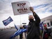 FILE - Supporters of President Donald Trump hold signs as they stand outside of the Clark County Elections Department in North Las Vegas,Nov. 7, 2020.