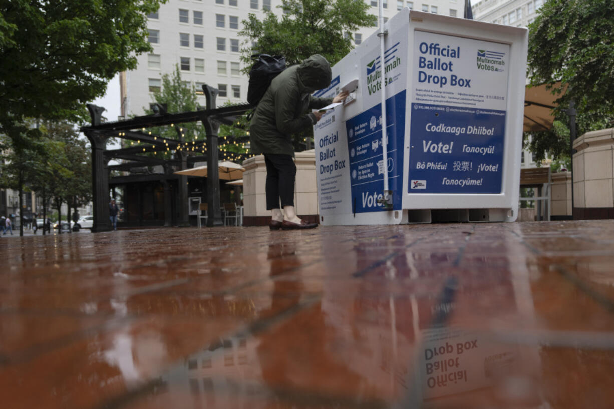 A person drops off a vote-by-mail ballot at a dropbox in Pioneer Square during primary voting on Tuesday in Portland.