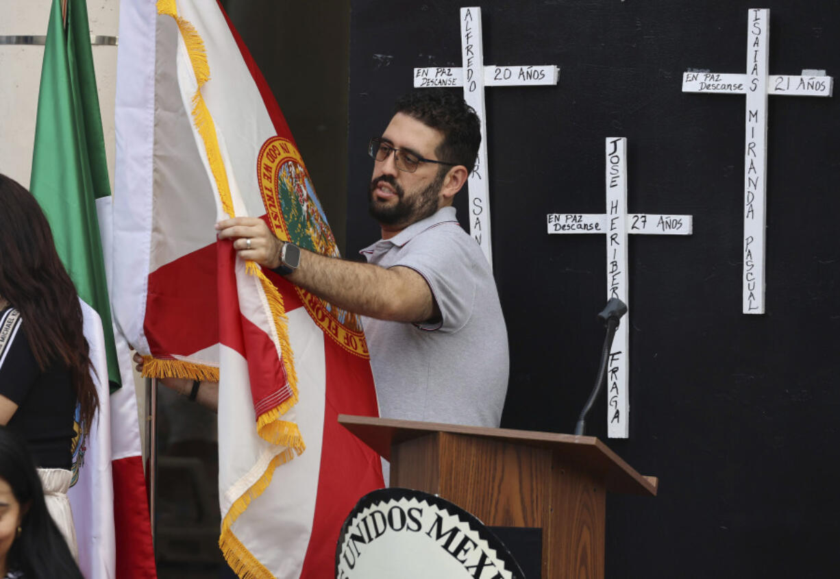 A flag is unfurled in front of the Mexican Consulate in Orlando, Fla., Tuesday, May 21, 2024, for a vigil honoring the eight Mexican farmworkers who were killed in a bus crash last week in Marion County. (Stephen M.