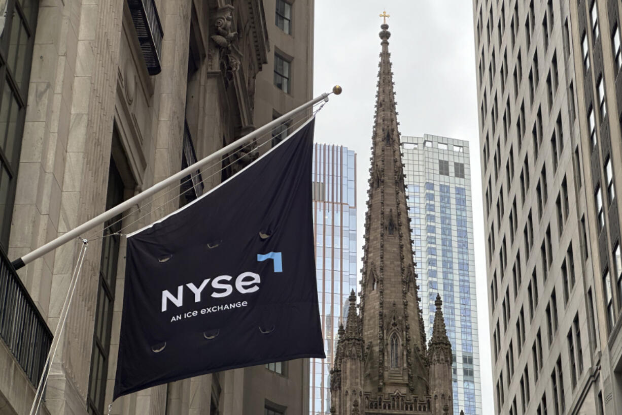 FILE - A flag hangs from the side of the New York Stock Exchange is on Thursday, May 16, 2024, in New York. Trinity Church appears in the background.